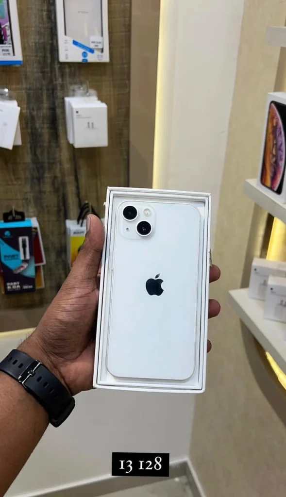 A person holfding a white smartphone with dual cameras placed inside its box.