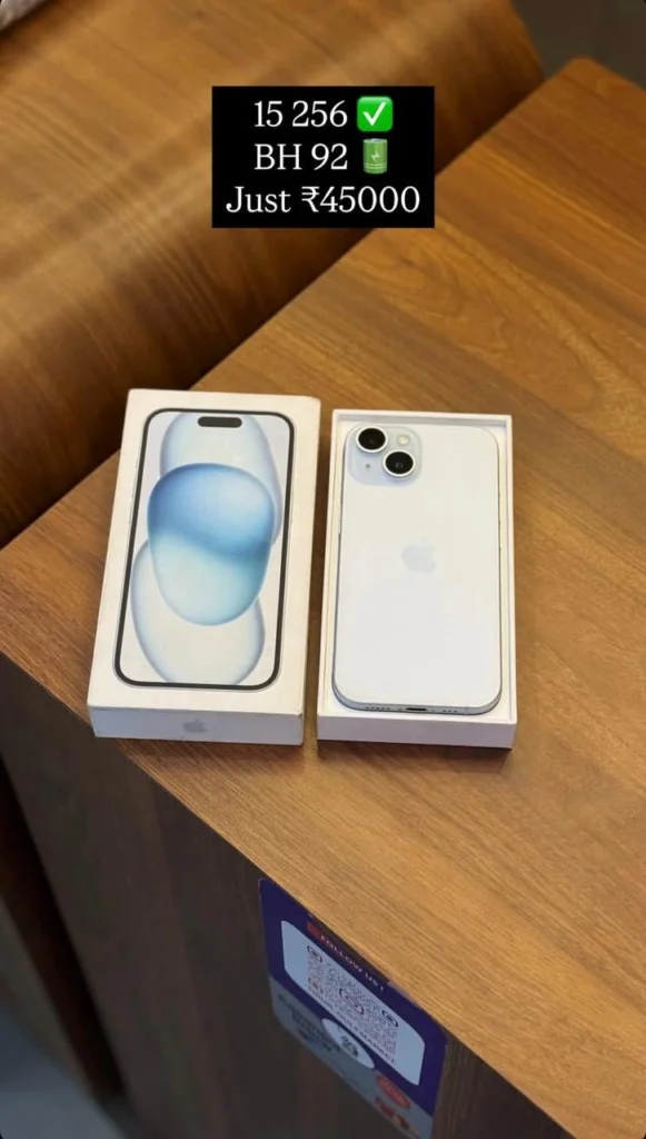 A new white iPhone placed in its open box next to the front cover of the packaging, displayed on a wooden table.