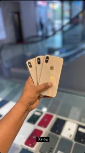 "A hand holding threegold-colored iPhone Xs ".